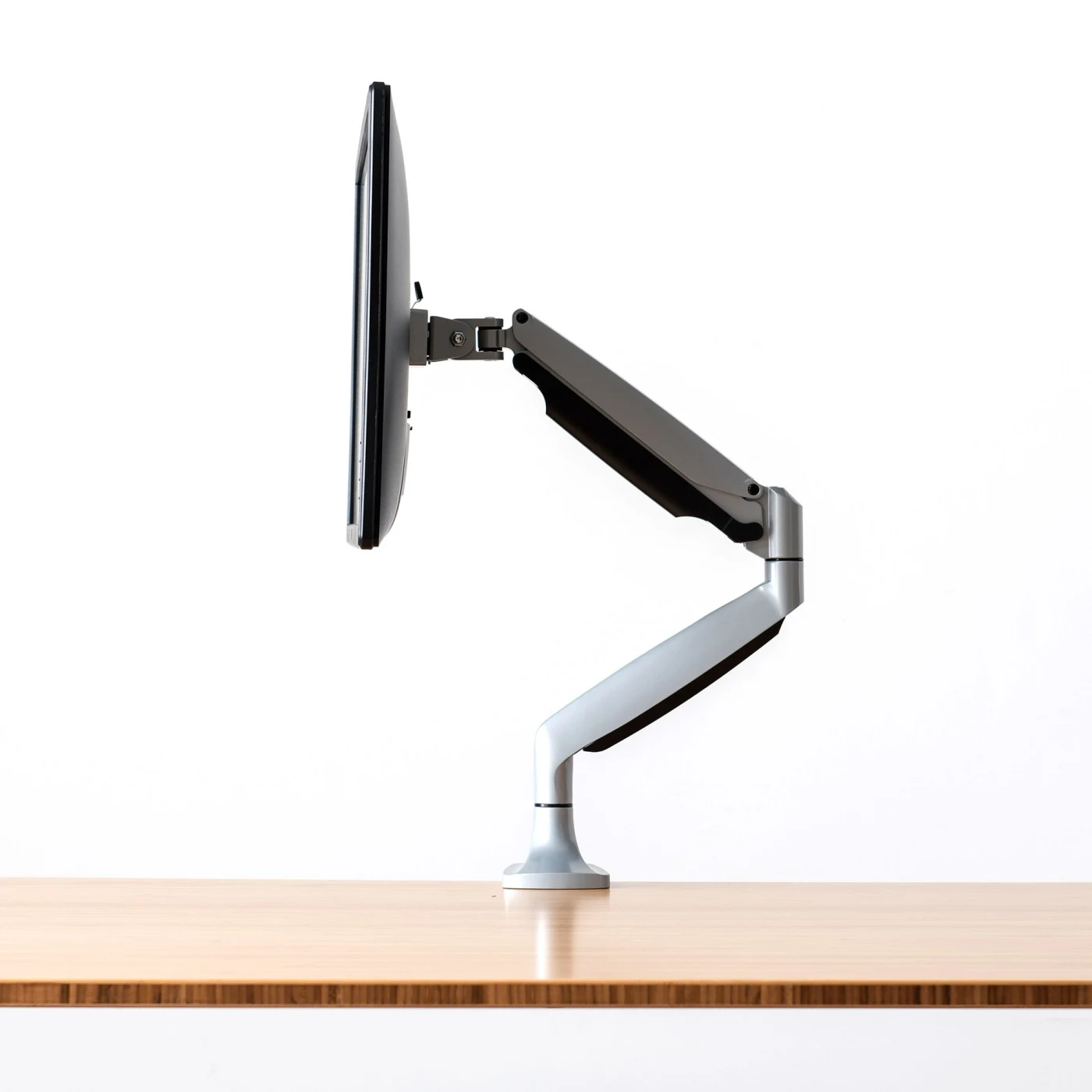 Monitor arm braced at a desk, holding a monitor sideways